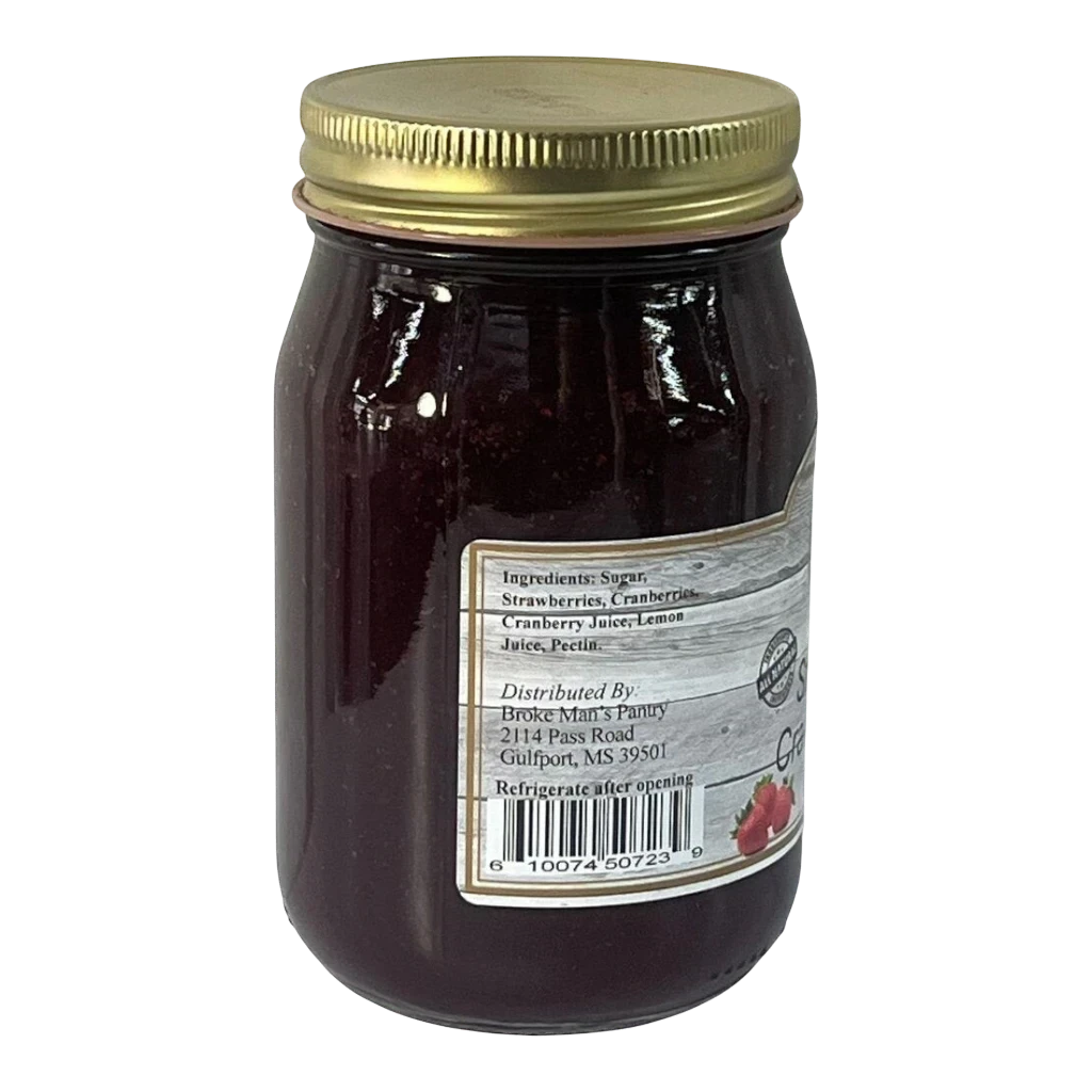 Broke Man's Pantry strawberry cranberry jam in a glass jar with a gold lid against a black background.