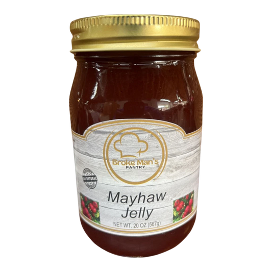 Broke Man's Pantry all-natural mayhaw jelly in a 20 oz glass jar with a gold lid on a rustic wooden surface.