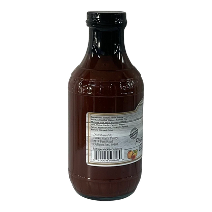 Broke Man's Pantry Peach Bourbon BBQ Sauce in a glass bottle with a detailed ingredient label on a black background.